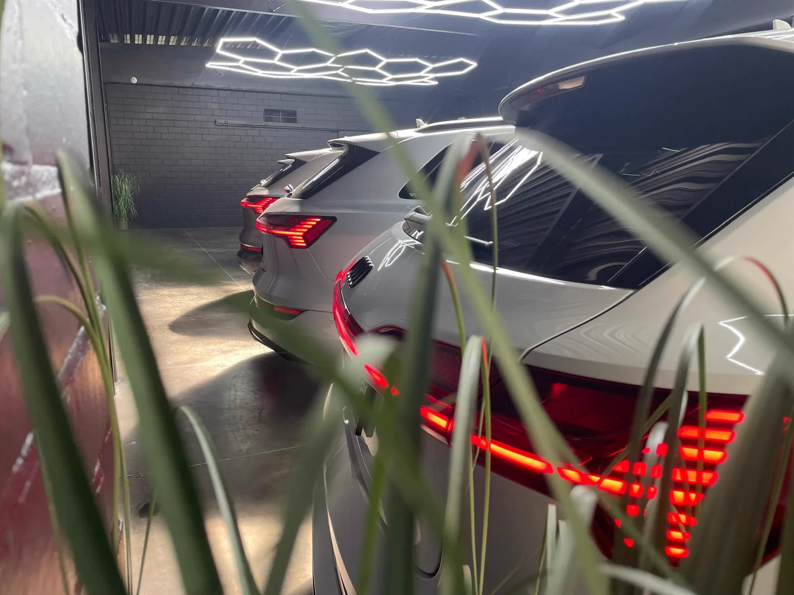 Rij witte Audi SUV's met brandende achterlichten in de showroom van Carcenter STV in Menen