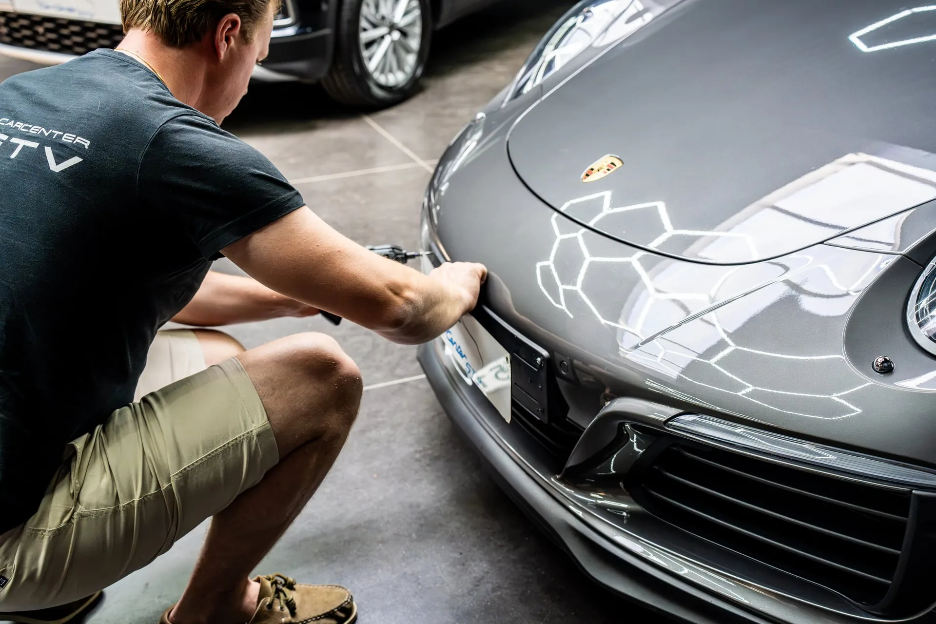 Medewerker van Carcenter STV maakt een Porsche klaar in de showroom in Menen