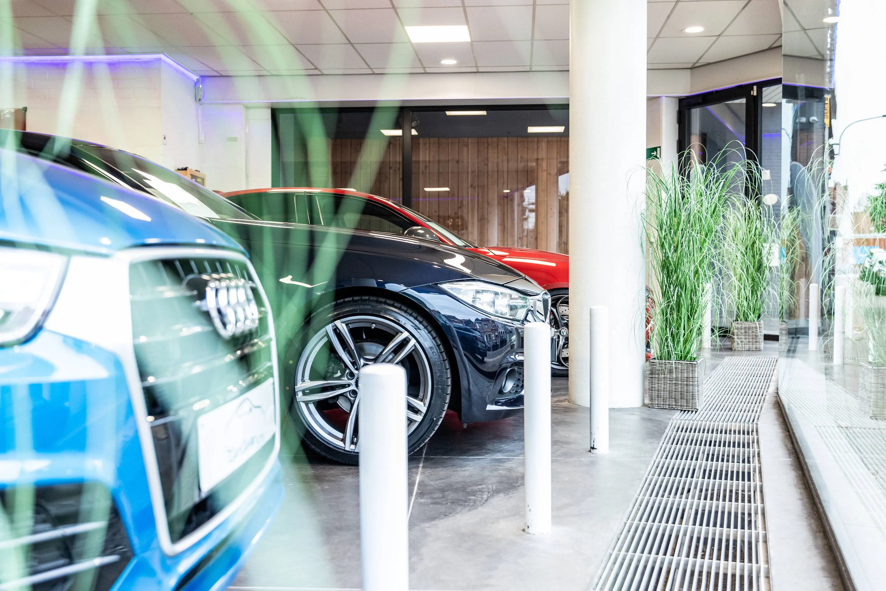 Drie glimmende premium wagens in een moderne showroom — Carcenter STV Menen