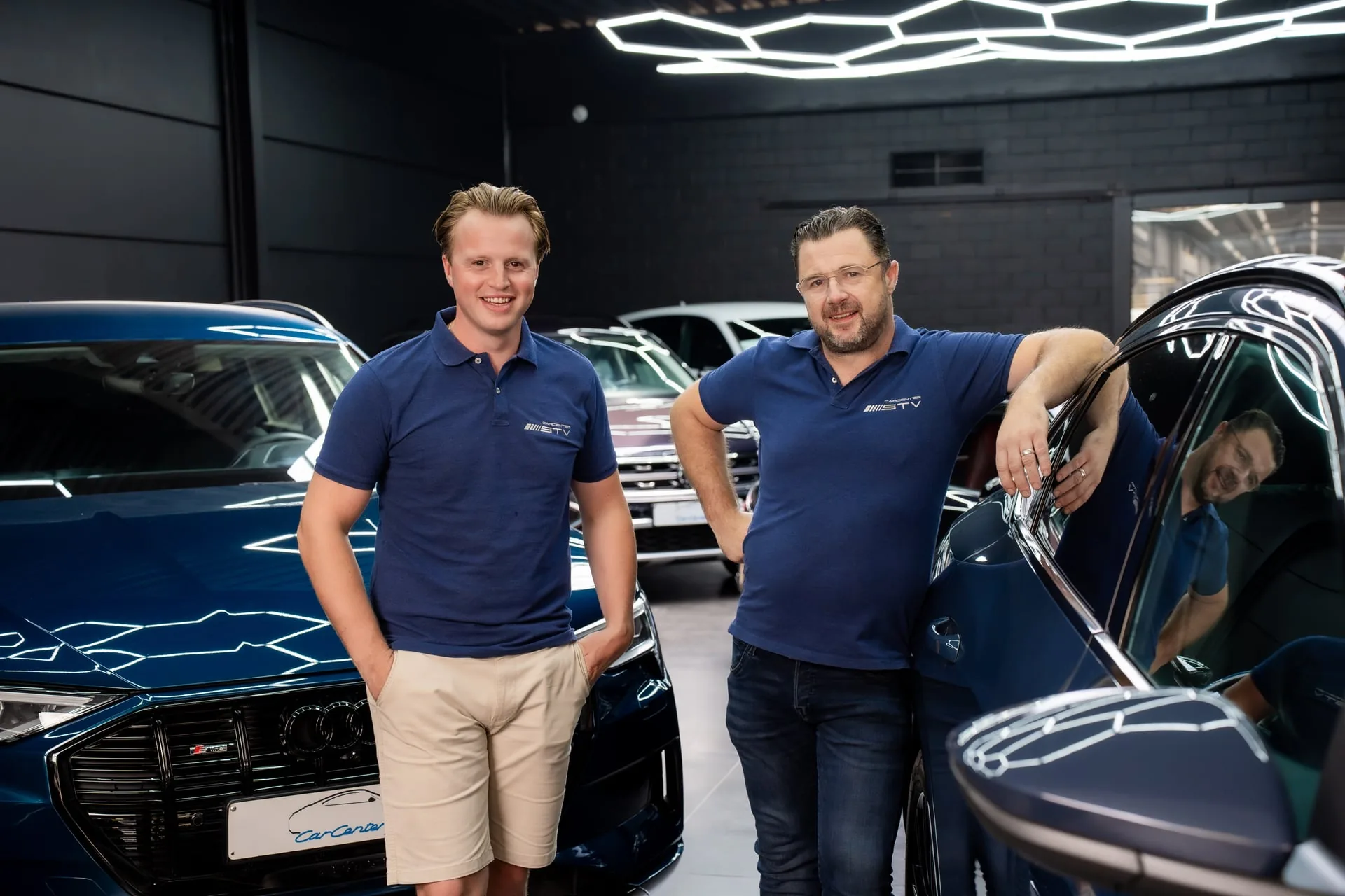 Thibaut en Steve van Carcenter STV in de showroom tussen premium wagens in Menen